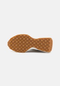 Pantofii sport albi, cu o talpă din cauciuc texturat, de culoare gumă, care dispune de cuie în formă de piramidă pentru aderență și un design elegant.