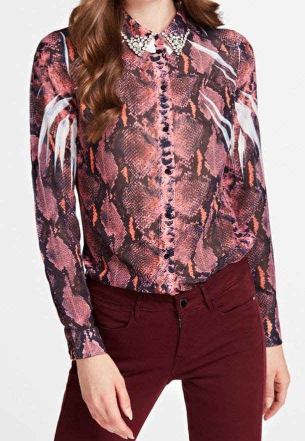 Chemise à manches longues avec un motif serpent rose et noir, présentant un col décoratif avec des accents de gemmes et des motifs ressemblant à des plumes blanches sur les manches.