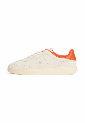 Sneaker beige con superficie liscia, accentuazione arancione sul tallone, punta arrotondata e suola piatta in gomma. Presenta una chiusura con lacci e fori di ventilazione discreti.