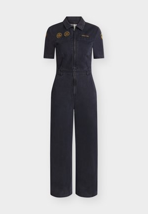 Tuta corta a maniche corte di colore blu navy scuro con cerniera frontale, tasche sul petto, passanti alla cintura e toppe ricamate gialle su petto e maniche.