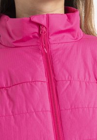 Fuchsiová zipová bunda s vysokým límcem, prošívaným designem a hladkým, lehkým materiálem s jemnou ribbovanou strukturou.