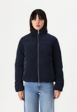 Navy corduroy puffer jacket with high collar, zip closure, and two side pockets, featuring a quilted pattern and ribbed texture.