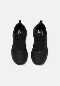 Chaussures de sport noires avec tige en maille, semelle rembourrée et design à lacets. Caractéristiques de finitions texturées sur le talon et la languette.