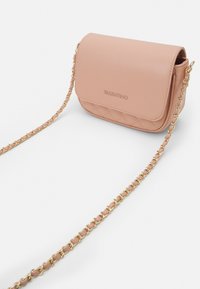 Sac bandoulière en simili cuir couleur pêche avec un design matelassé, une chaîne dorée et une fermeture à rabat magnétique. Présente un logo de marque en relief.