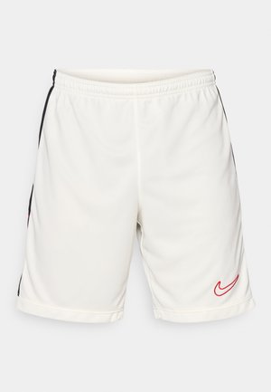 Bijele atletske hlačice od glatkog materijala s crnim bočnim prugama i crvenim Nike logotipom na donjem lijevom rubu. Uključena elastična uže.