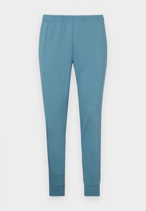 Pantalones de chándal azul claro fabricados en un tejido suave, con un diseño ajustado, cinturilla elástica y dobladillos con puños. Logo pequeño en un lado.
