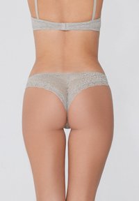 Grijze kanten string met ingewikkelde bloemenpatronen, met een zachte elastische tailleband. Het materiaal is delicaat en semi-doorzichtig.