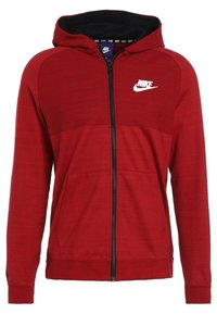 Červená mikina na zip s kapucí s černým lemem, předními kapsami a bílým logem Nike. Vyrobena z texturované tkaniny s kontrastním designem panelů.