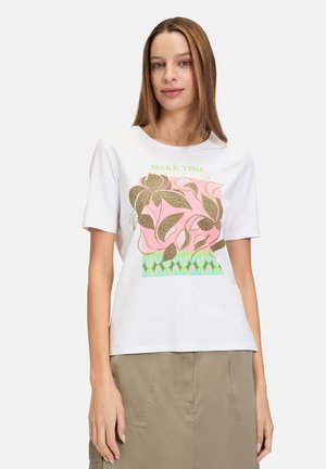 T-shirt en coton blanc avec un design graphique coloré comprenant des feuilles roses et un texte vert portant la mention "FAITES DU TEMPS" sur le devant. Manches courtes.