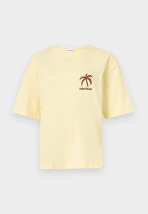 T-shirt a maniche corte giallo pallido con grafica di palma marrone e testo "Palm Beach" sul lato sinistro del petto.