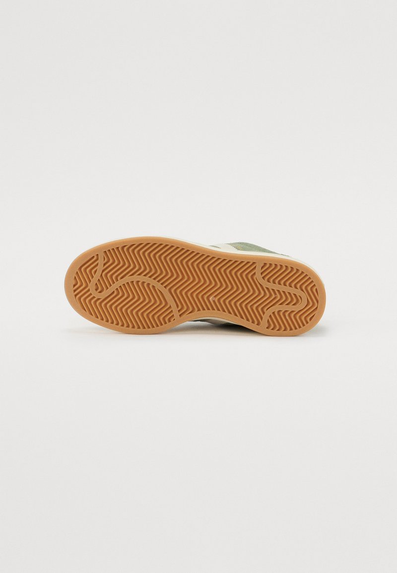 Suela de zapato de goma con un patrón de espiga, de color marrón claro. El diseño es plano con un acento de tela verde en la parte superior.