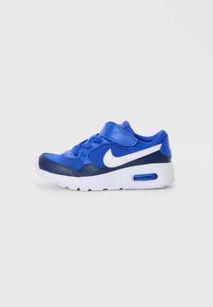 Baskets de sport pour enfants en bleu et marine avec une semelle blanche et le logo Nike Swoosh, dotées de lacets et d'une sangle Velcro.