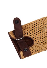 Brown leather strap with snap button, securing a woven, light tan crochet fabric. The shape is rectangular with open weave texture.