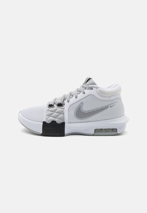 Zapatilla deportiva en gris y blanco con parte superior de malla, textura acolchada, suela de goma negra y amortiguación de aire visible en el talón.