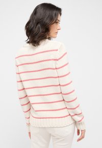 Gestreifter Strickpullover in Creme mit rosa Streifen, mit hohem Kragen, gerippten Bündchen und Saum, der eine lockere Passform und einen strukturierten Stoff präsentiert.