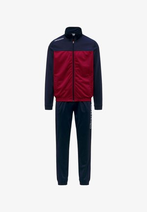 Survêtement avec une veste zippée bleu marine et rouge et un pantalon bleu marine assorti, présentant des logos Kappa blancs sur la poitrine et la jambe.