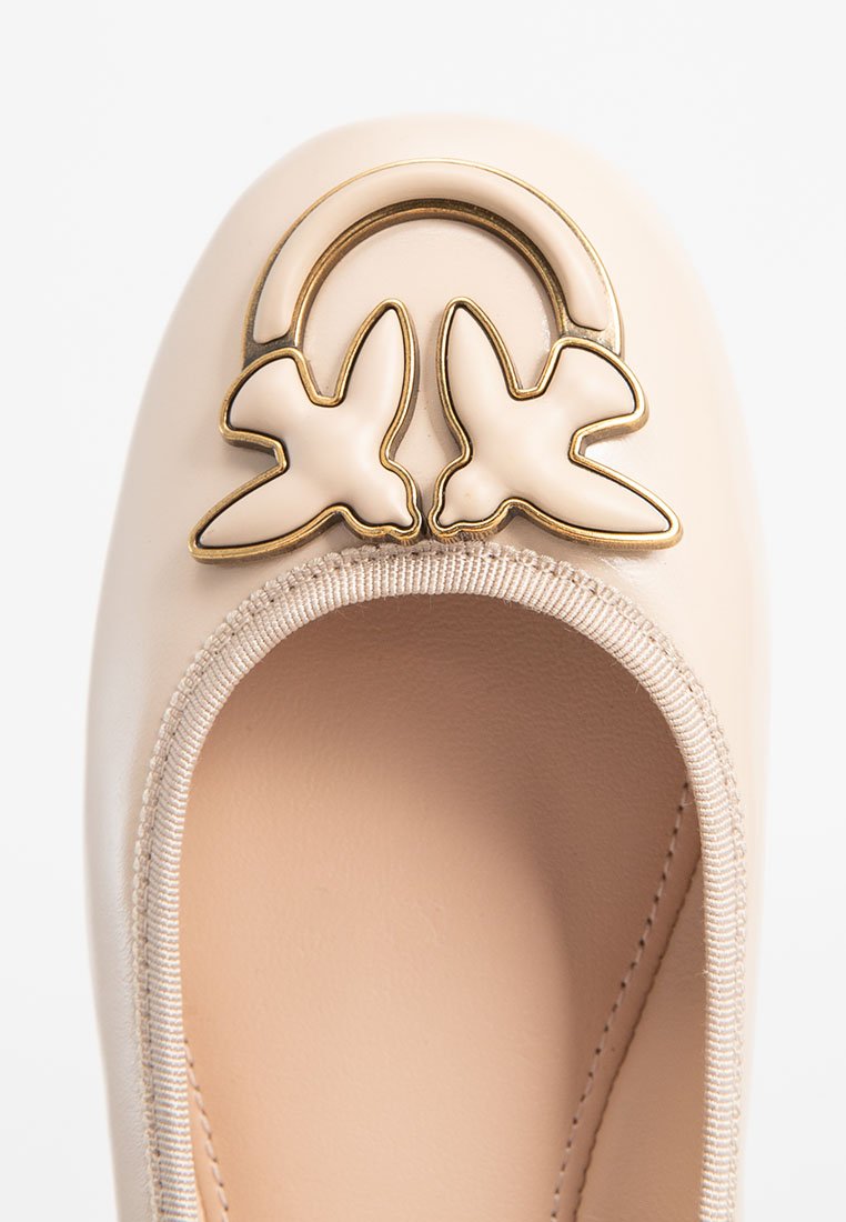 Bailarinas de un tono beige claro con punta redondeada, que presentan un detalle de hardware en tono dorado en forma de mariposas y una abertura elástica cosida.