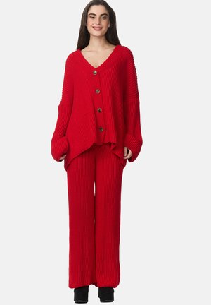 Ensemble en deux pièces en tricot rouge comportant un cardigan ample à col en V avec des boutons et un pantalon à coupe décontractée, tous deux avec une texture côtelée.