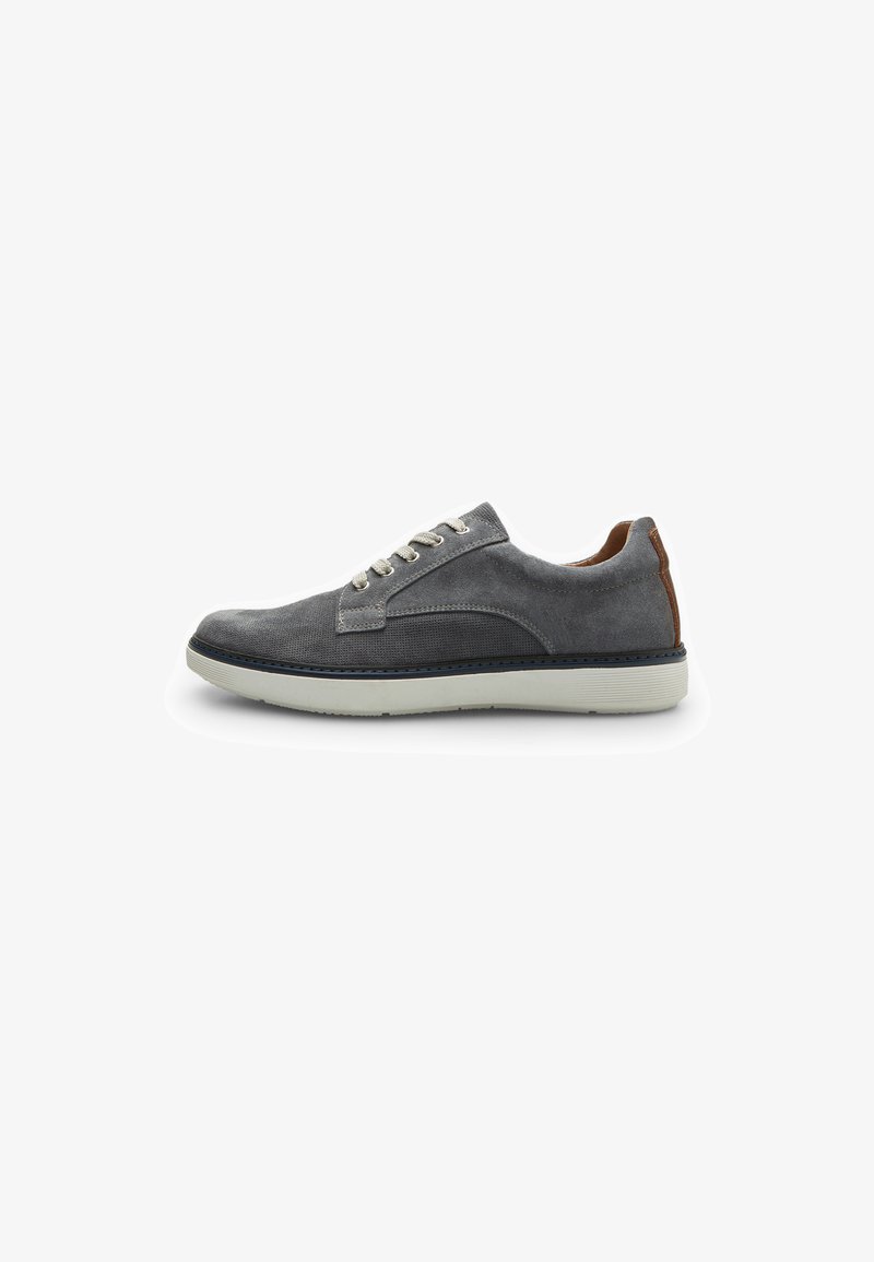 Zapatilla de ante gris con una textura suave, punta redonda, suela de goma blanca y un acento en el talón de piel marrón en contraste. Ojetes de metal para los cordones.