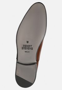 Semelle en cuir marron avec une semelle intérieure grise texturée, logo embossé "HENRY STEVENS" et petits clous en métal le long du bord.