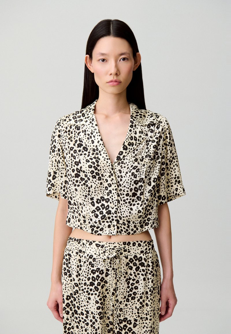 Camisa de manga corta y corta, y pantalones a juego en tela suave y ligera con base beige y manchas de leopardo negras.