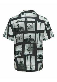 Camisa de manga corta con un patrón de collage fotográfico en blanco y negro que presenta escenas de surf y palmeras sobre una tela suave.