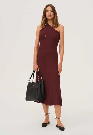 Robe midi bordeaux à côtes avec encolure asymétrique et détail en trou de serrure, associée à un sac fourre-tout noir et des ballerines noires texturées.