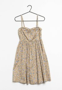 Valkoinen kukkamekko, jossa on ohuet olkaimet, rypistetty rintaosa ja hulmuava helma. Kankaassa on sinisiä ja valkoisia kukkakuvioita.