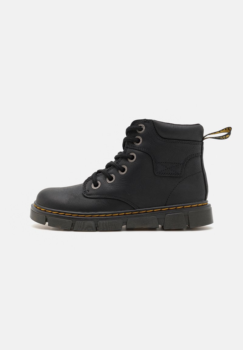 Bottine noire en cuir avec une semelle épaisse texturée, fermeture à lacets sur le devant, col rembourré et surpiqûres jaunes le long du bord de la semelle.