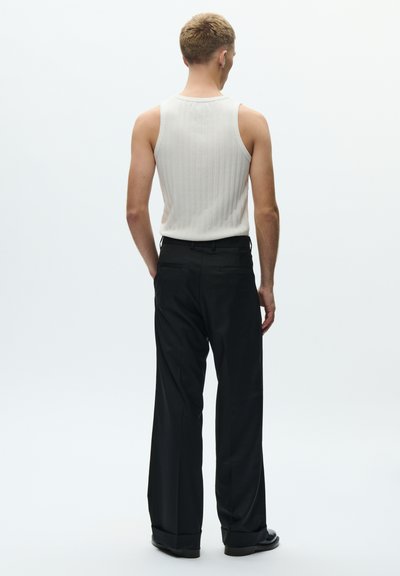 Hvid ribbet tanktop kombineret med sorte bukser med brede ben; synligt taljebånd og afslappet pasform med en glat tekstur og minimal detaljering.