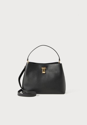Sac à main en cuir noir avec une forme structurée, fermoir en métal doré, anse courte et une bandoulière amovible. Détails de texture en surface.