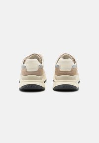 Beige und cremefarbene Sneaker aus Wildleder und Leder. Abgerundete Form, gepolsterter Schaft und strukturierte schwarze Gummisohle.