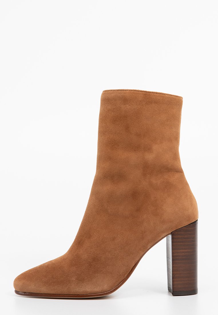 Botte chelsea en daim marron avec un bout pointu, une tige courte et un talon bloc solide présentant une texture ressemblant à du bois. Surface lisse, design minimaliste.