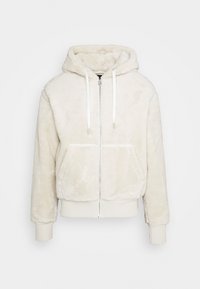 Cremefarvet zip-hoodie lavet af blødt, fluffy materiale. Har en hætte, to forlommer og ribbede manchetter og talje.
