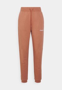 Calvin Klein joggerit tumman oranssina, valmistettu pehmeästä kankaasta, jossa on joustava vyötärö, naru ja ribbauslahkeet.