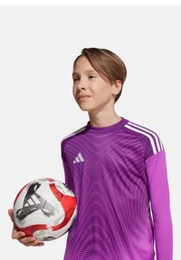 Maillot de football violet à manches longues avec un design dégradé et un logo sur la poitrine, tenu avec un ballon de football multicolore avec des accents noirs.