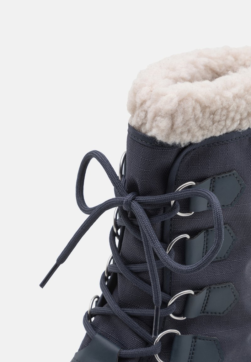 Granatowe buty za kostkę na sznurowanie z miękkim, kremowym wnętrzem, teksturowanym materiałem, metalowymi oczkami oraz wyraźnym kształtem z dekoracyjnymi akcentami.