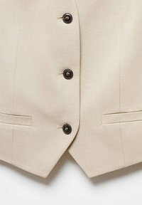 Beiger Blazer aus glattem Stoff, mit fünf schwarzen Knöpfen, zwei Seitentaschen und taillierten Kanten für eine strukturierte Silhouette.