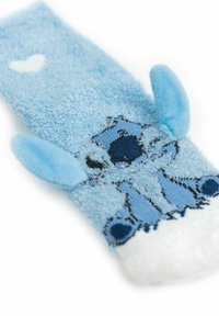 Calzino blu peloso con una superficie testurizzata caratterizzato da un personaggio ricamato, orecchie sovradimensionate e un dettaglio a cuore di colore bianco.