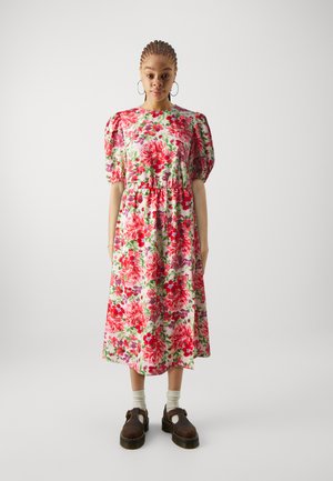 Floral dress with short puff sleeves, cinched waist, features bold pink and red flowers on a light background. Paired with brown shoes and white socks.