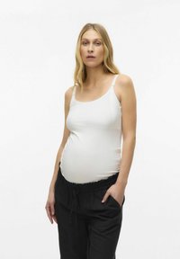 Canotta bianca premaman con spalline regolabili, texture morbida e design aderente, abbinata a pantaloni neri larghi con vita elastica.