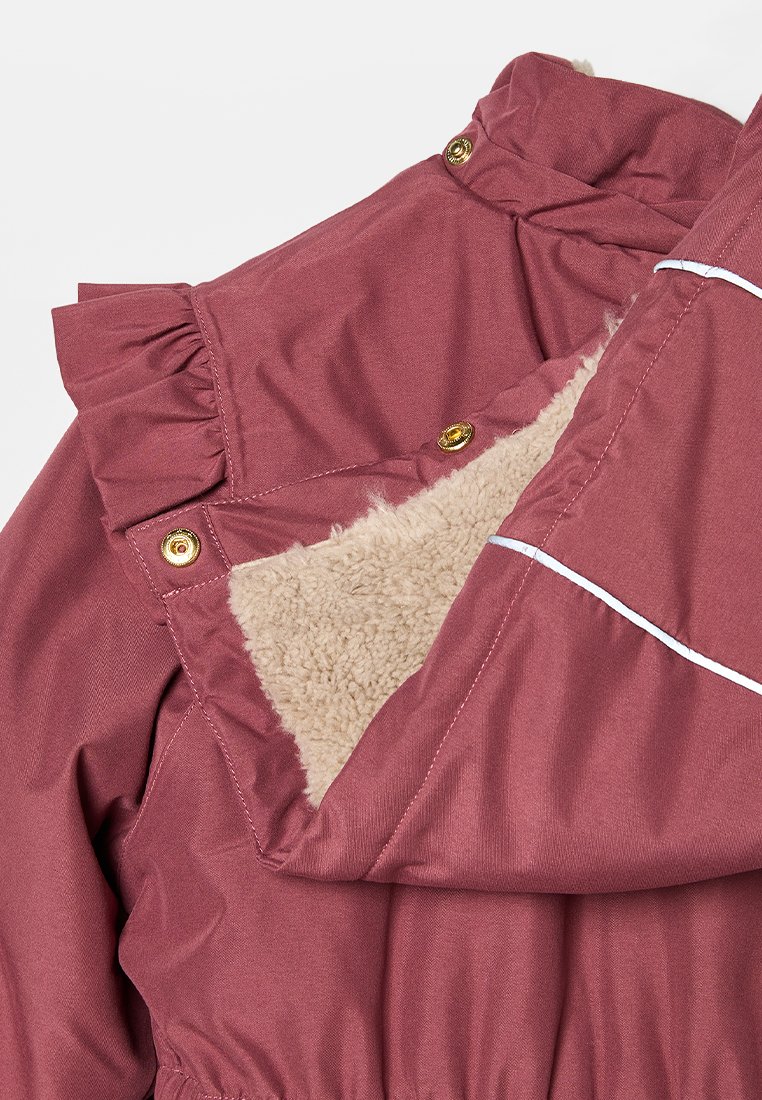 Roze jas met een geschulpte kraag, voorzien van gouden hardware en een zachte beige fleece voering. Het exterieur is glad met witte accenten.