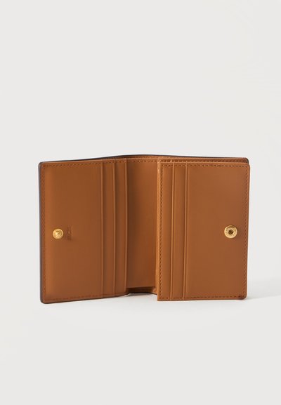 Portefeuille en cuir marron ouvert montrant plusieurs emplacements pour cartes et une fermeture à bouton-pression sur un fond clair uni.