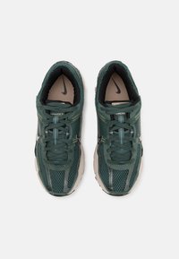 Paire de chaussures de course Nike vertes avec doublure intérieure noire, tissu en mesh et lacets, vues de dessus sur fond blanc.