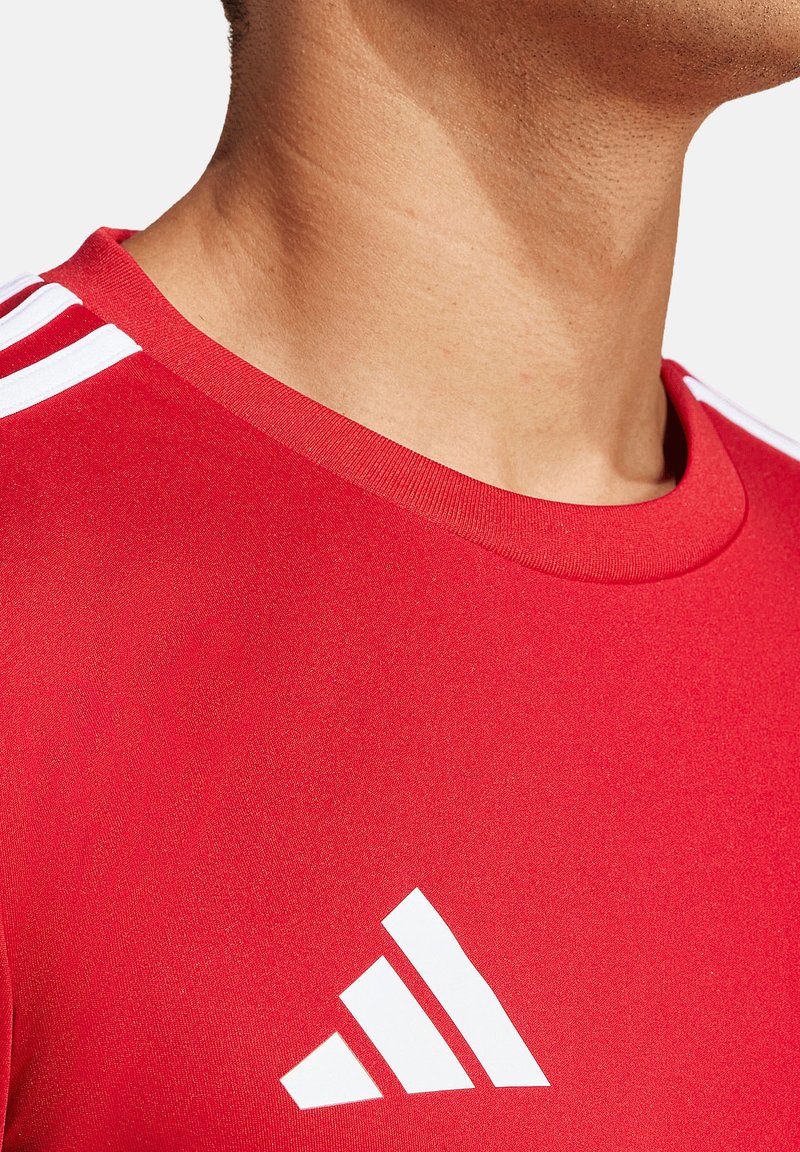 Rotes Sportshirt mit rundem Halsausschnitt, glatter Textur und weißem Adidas-Logo sowie drei weißen Streifen auf den Schultern.