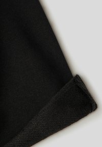 Tessuto nero con una consistenza liscia, caratterizzato da un polsino con un bordo testurizzato. Il materiale è lavorato a maglia con una finitura uniforme.