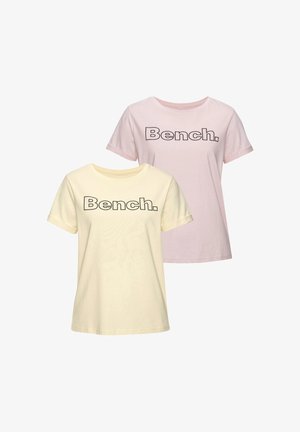 Two short-sleeve crew-neck T-shirts, one light yellow and one light pink, each with "Bench." printed in bold black letters.