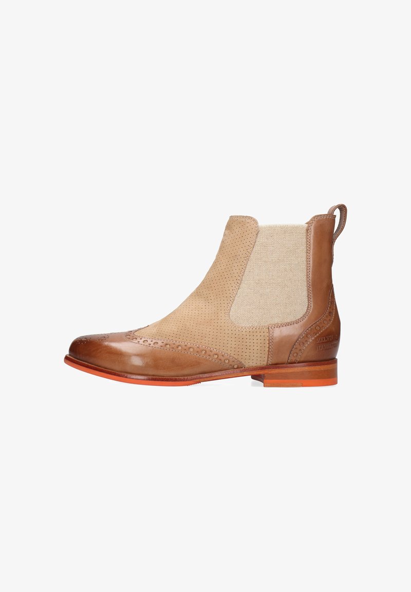 Bota Chelsea de cuero en tonos marrón y beige con detalles perforados, panel elástico lateral, lengüeta para tirar y tacón bajo apilado sobre fondo blanco.