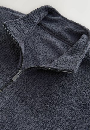 Dark gray fleece pullover with a high collar and half-zip closure. Textured fabric with ribbed lines and a flat zipper pull accent.