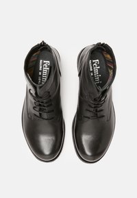 Botas de tobillo de cuero negro con cordones y cierre de cremallera. Textura suave con punta redondeada, con un forro interior de estampado.